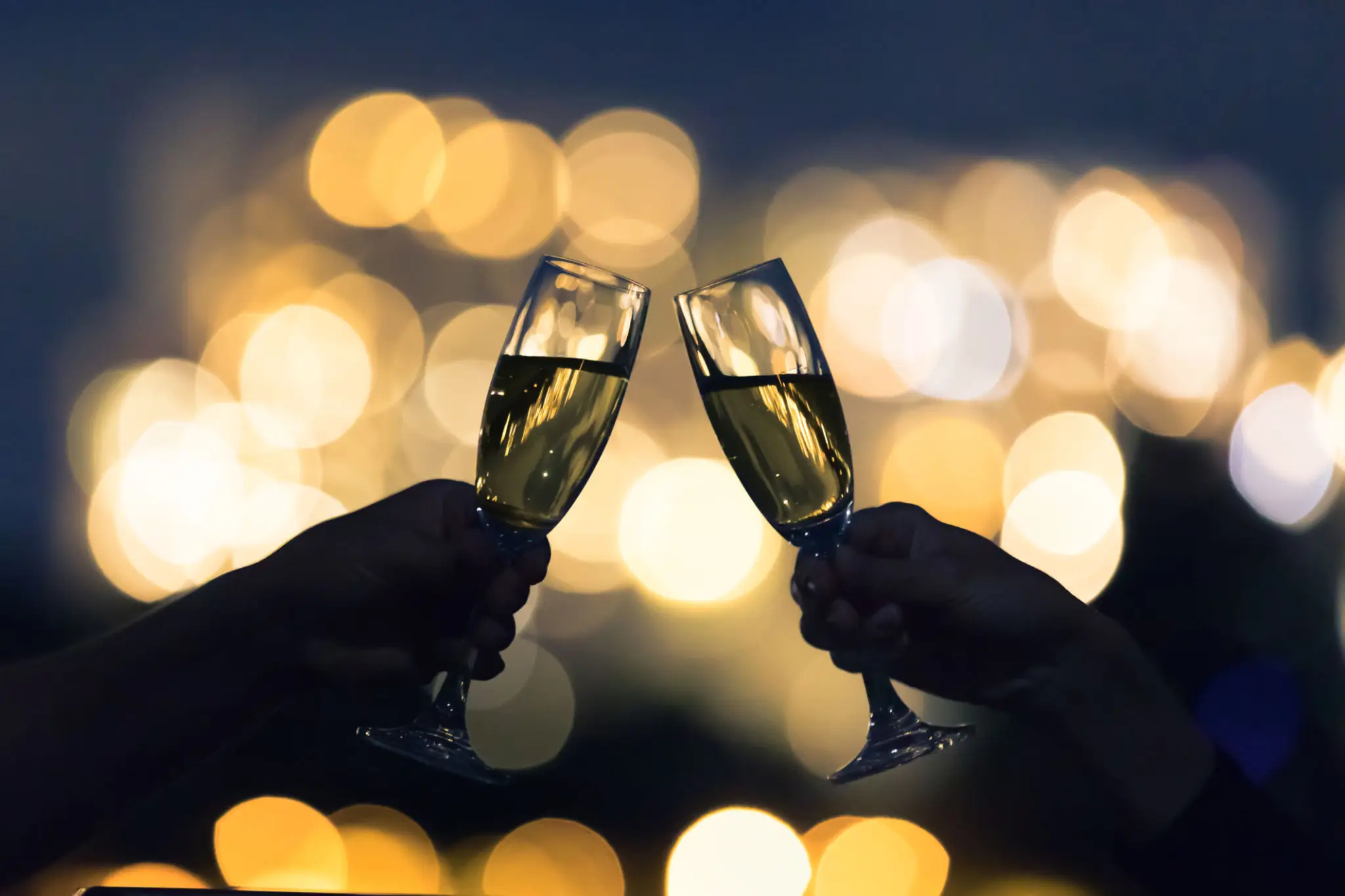 Toasting champagne glasses with bokeh lights background.
