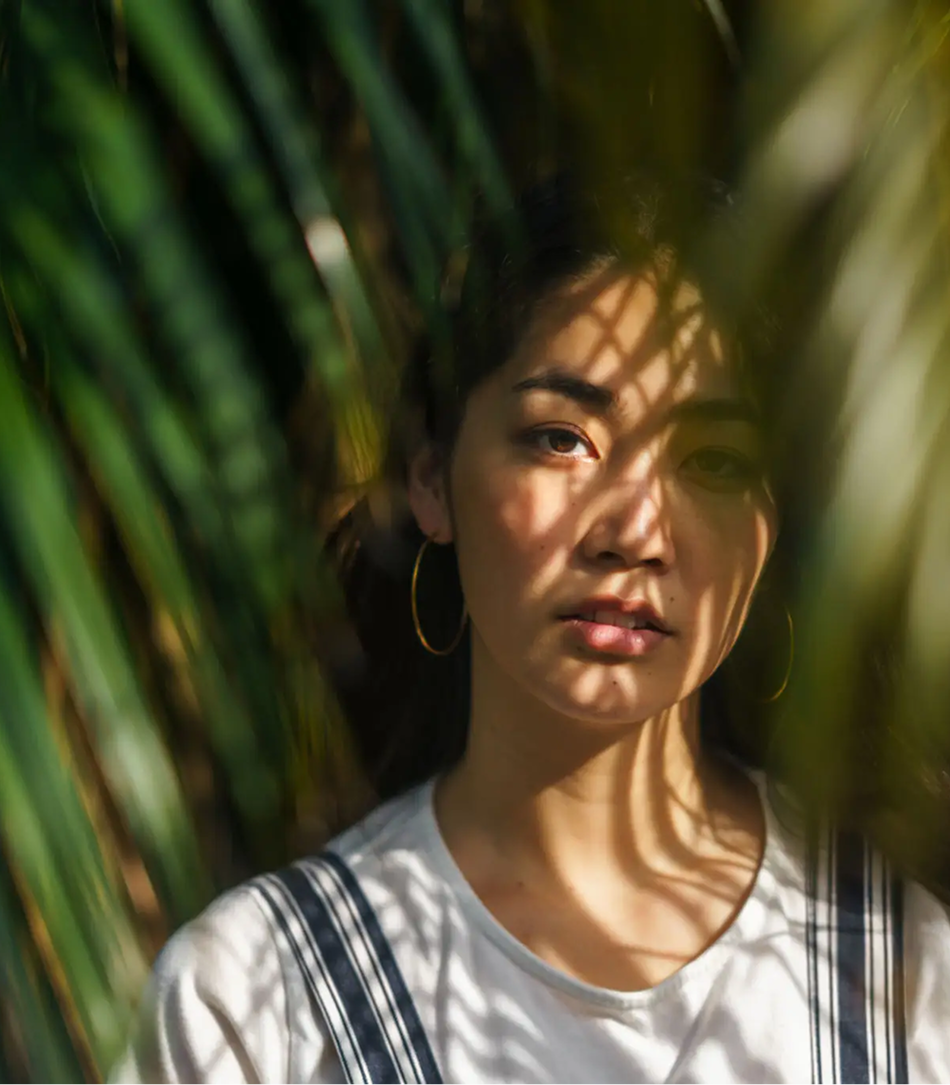 Shadowed face amidst green foliage
