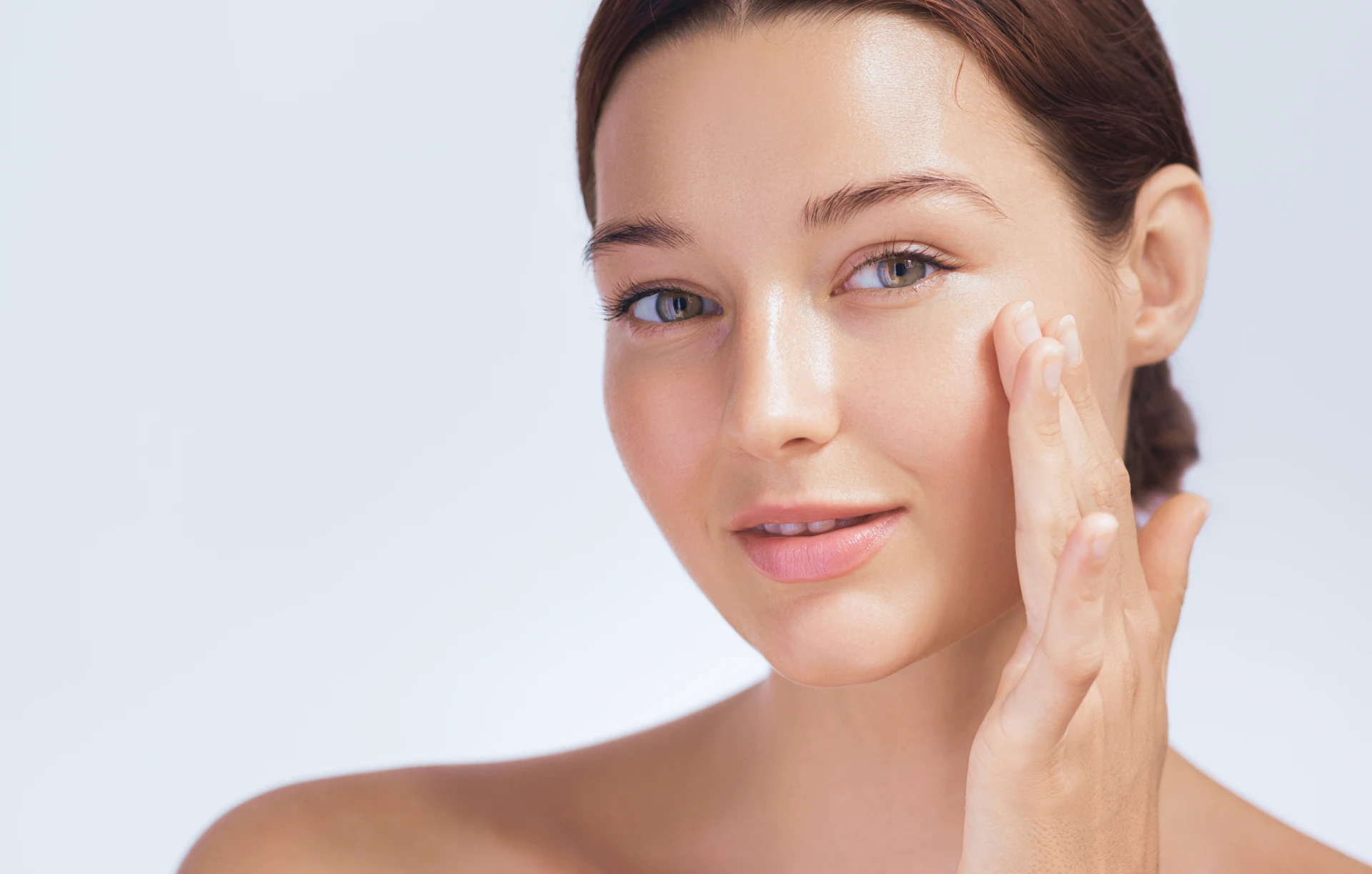 Young woman with clear skin touching face